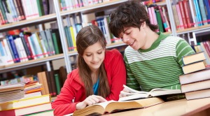 Portrait of teenage girl reading book with her classmate near by